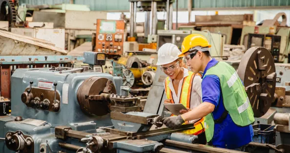 Industrial worker using a laptop in a manufacturing environment.