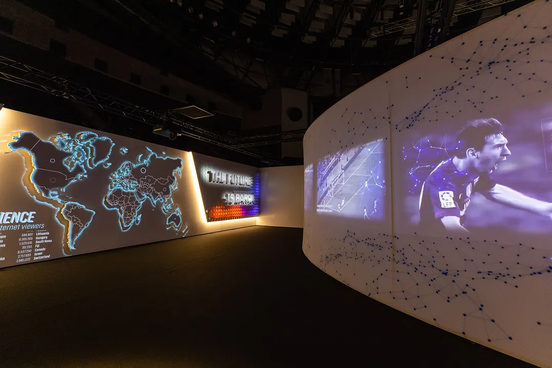 Exhibition room with a projected world map and a football player on an angled wall