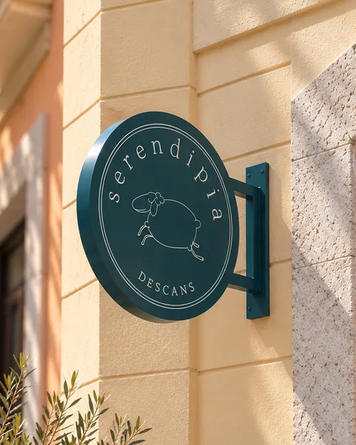 Round teal Serendipia Descans storefront sign with a sheep emblem.
